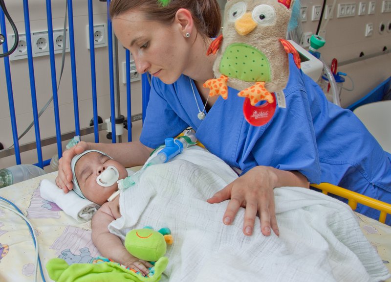 eine Krankenschwester beugt sich über ein Baby